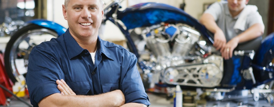 A mechanic standing in front of a motorcycle in his shop - The Bridge Auto Philadelphia